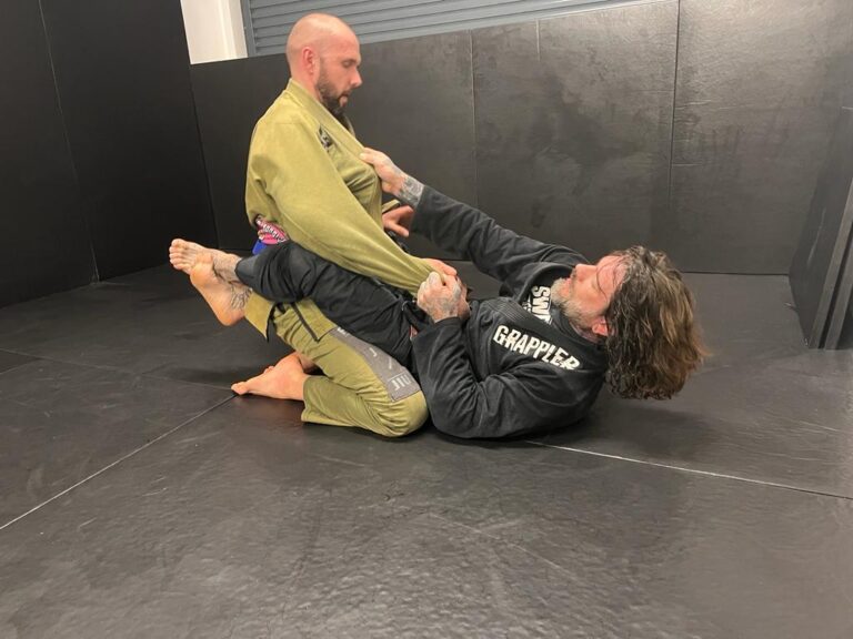 A pair of students practise Brazilian jiu-jitsu on the mat.