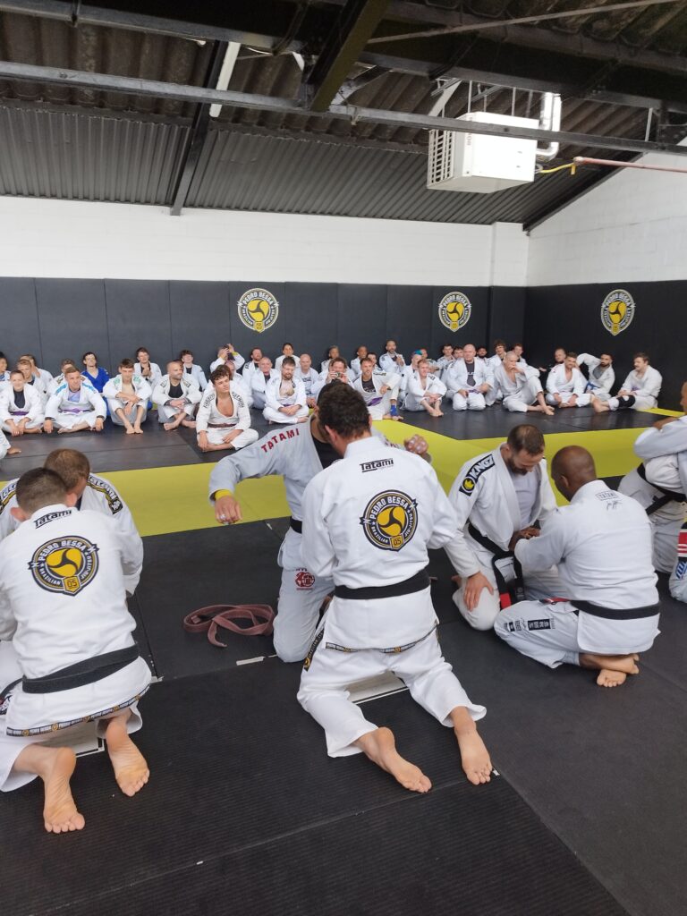 A coach teaches a technique to students on the mat.