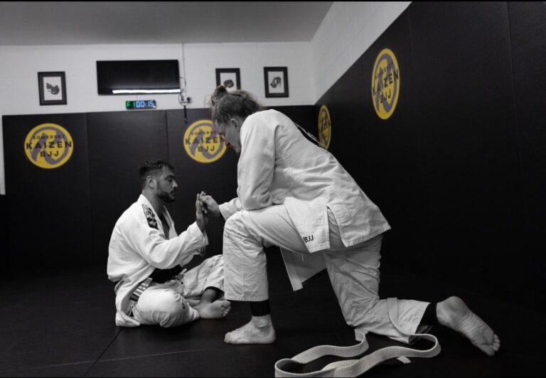 A coach demonstrates a Brazilian jiu-jitsu technique to students.